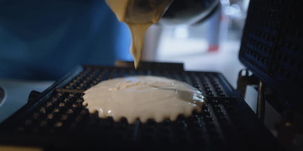 A person is cooking waffles in their kitchen