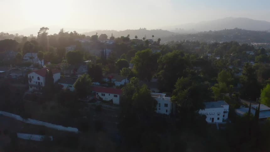 Parked cars line streets on town occupying hills on foggy day