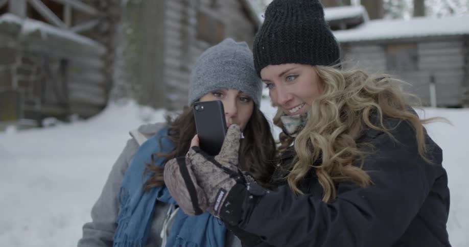 Two woman look and laugh at something on a phone