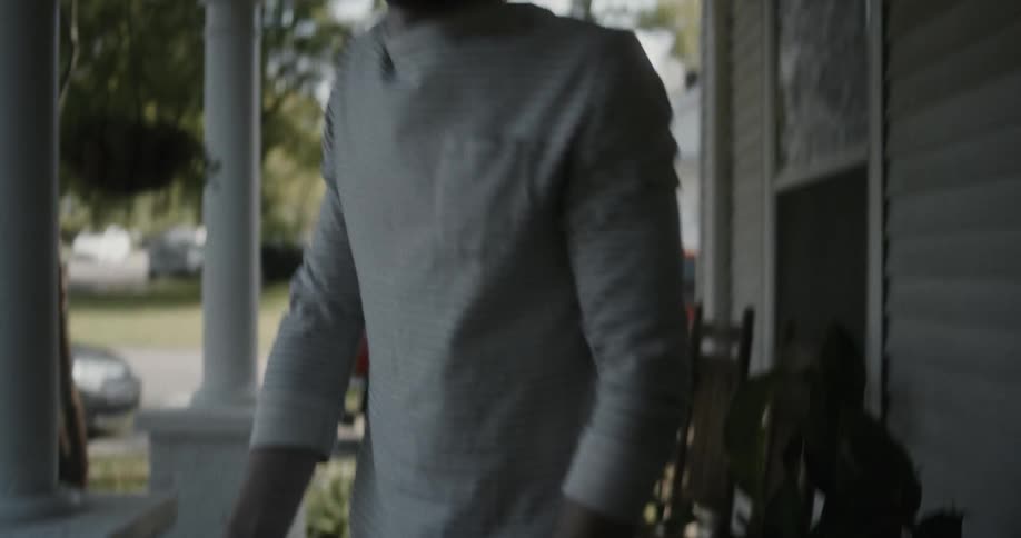 A man is picking up a package that is by his house