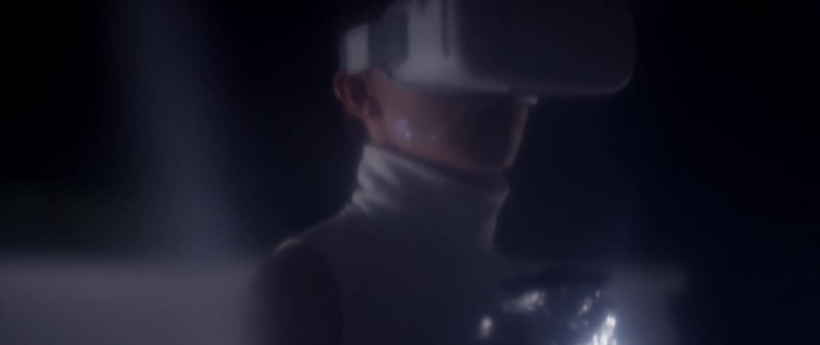 A woman in a room wrapped in a thermal blanket with a vr headset and a wall in the background