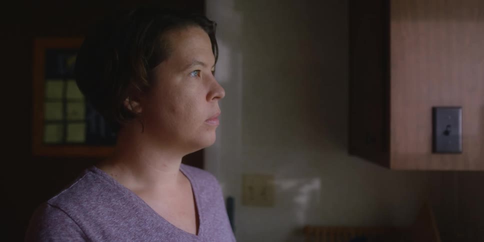 A woman stands in her kitchen and looks out the window