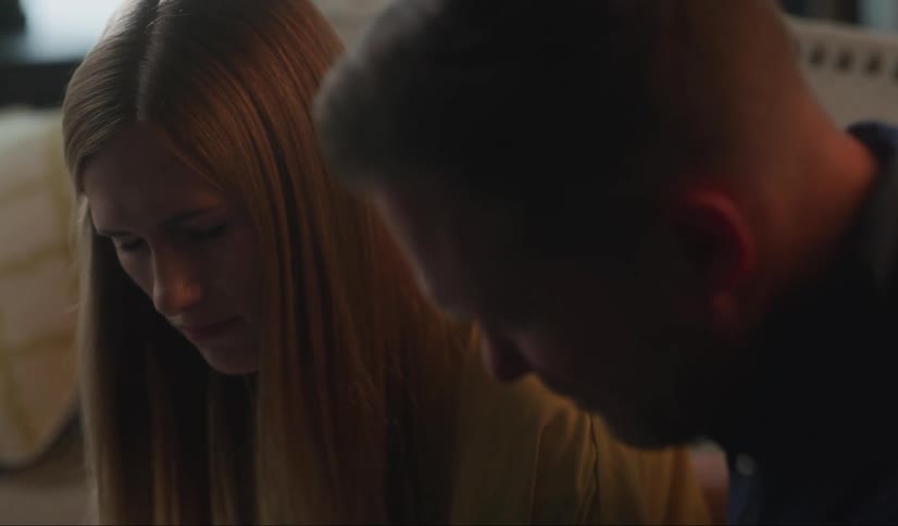 A man tries to comfort a young woman with a hug after she reads an upsetting letter but a glare from her stops him