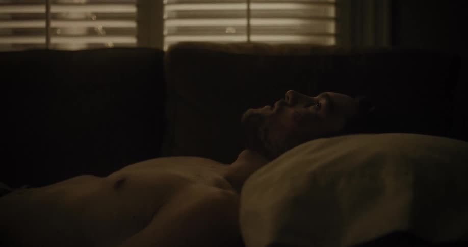 A man is laying down on a couch at night