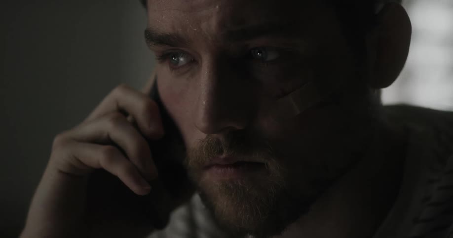 A man looking around a room anxiously and rocking while on the phone indoors