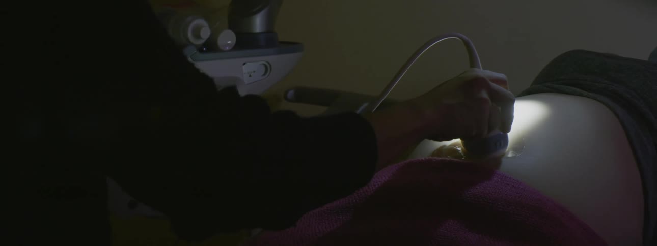 A woman in a clinic getting an ultrasound on her stomach