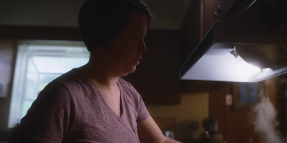A woman is in her kitchen and making tea