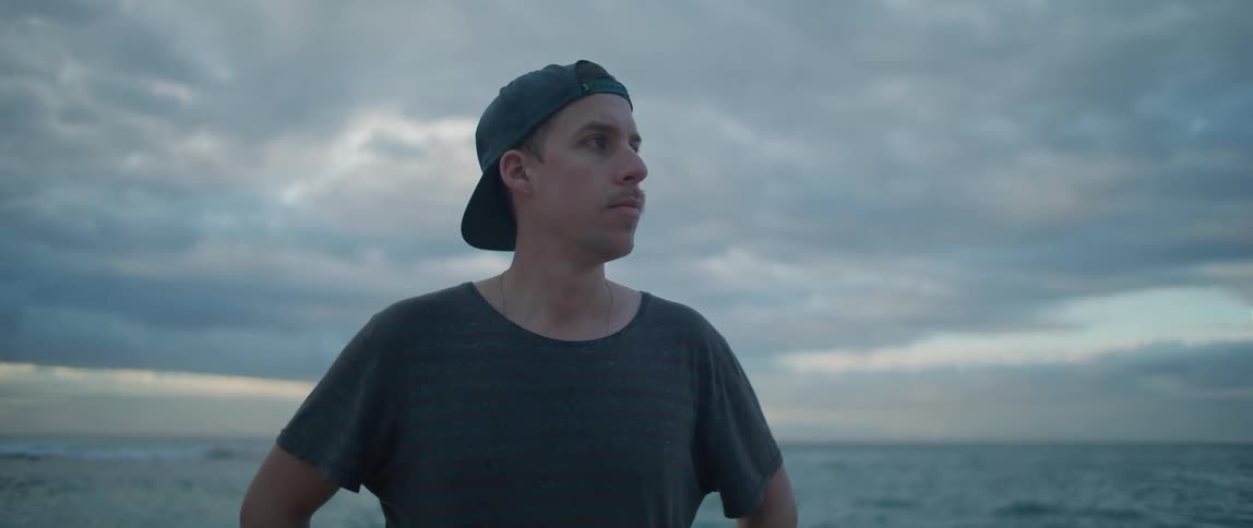 A man is standing outdoors by the ocean