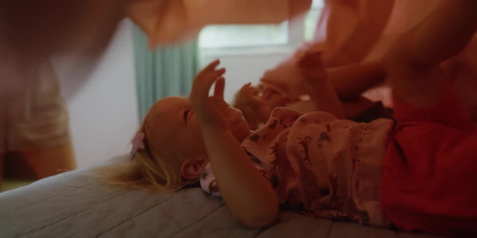 Mother playing with their daughters over the bed at home
