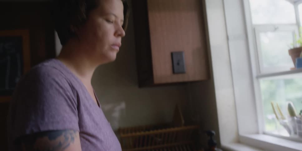 A woman is filling a tea kettle by a window