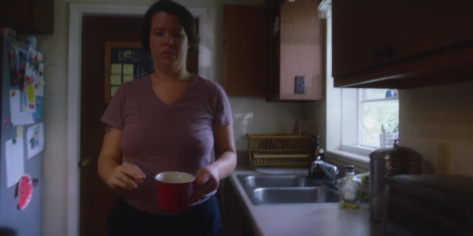 A woman removes a mug from the cabinet