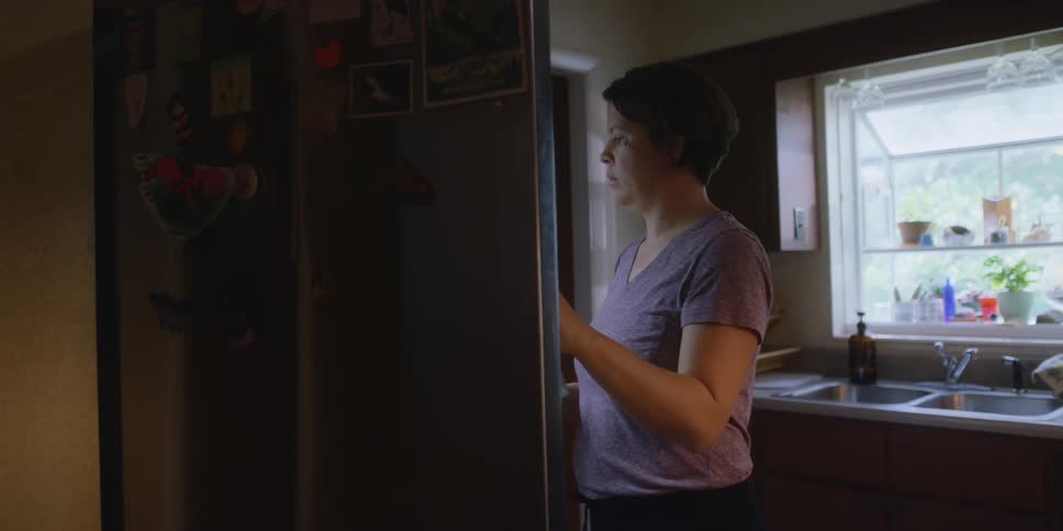 A woman is taking items from the fridge