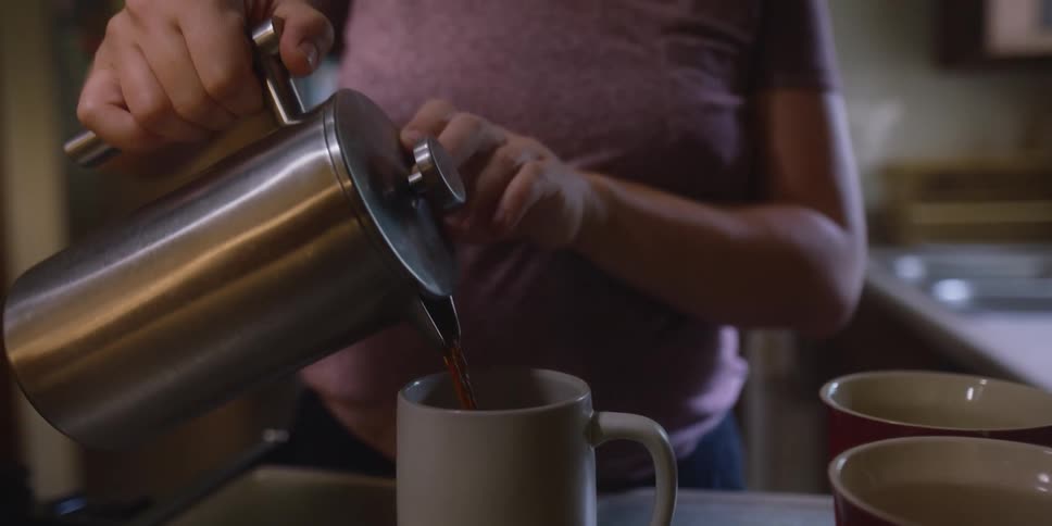 A woman is pouring coffee in her kitchen