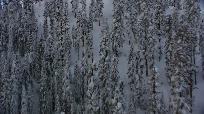 An aerial view of a mountain range during the winter with snow on them