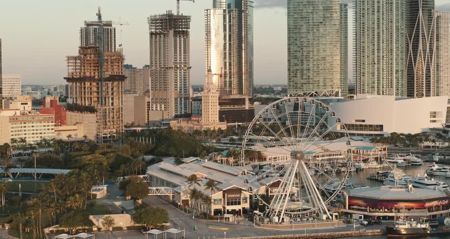 A city near the coast with a ferris wheel buildings and skyscrapers with the sky and clouds in the background
