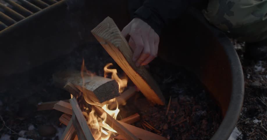A person stacks firewood in a bin