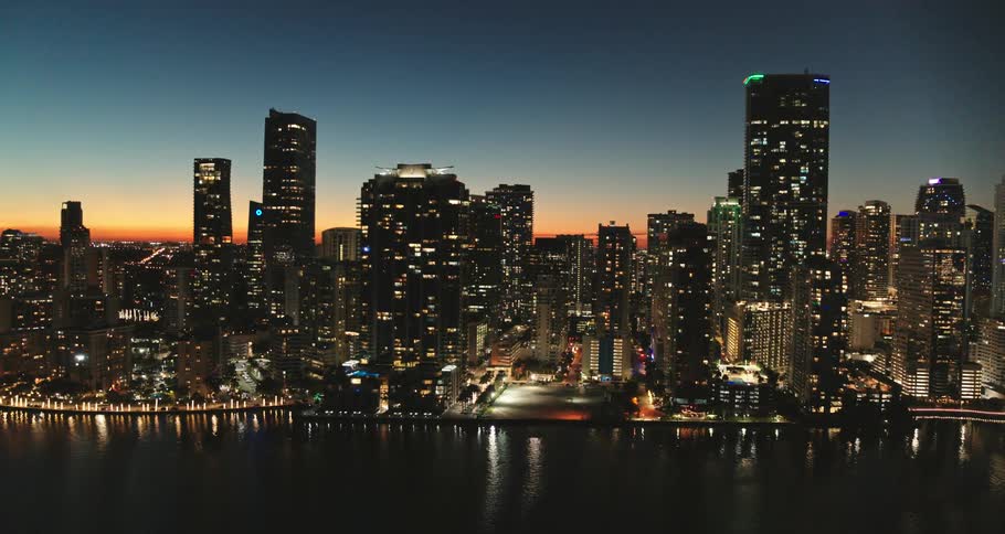 Water reflects city lights as red tint fills the horizon in background