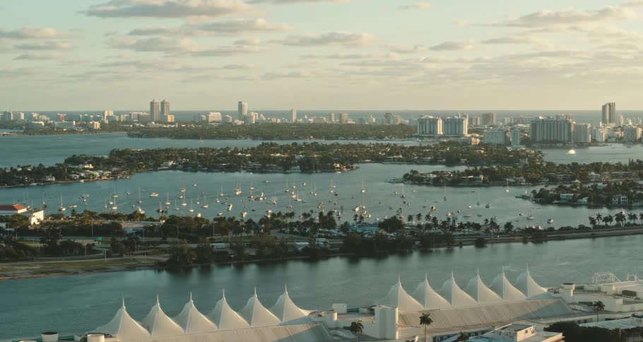 An aerial view of a water way with vehicles driving past and a city skyline in the distance