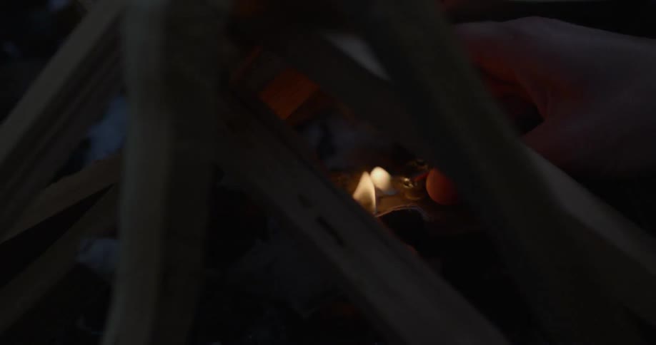 A lighter is used to ignite a campfire
