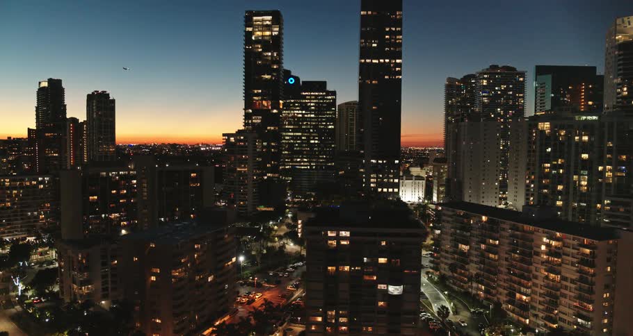 A city skyline with buildings and skyscrapers with a aircraft the sky and clouds in the background