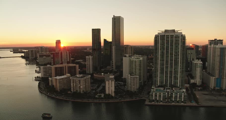 Bright sunrise shining on oceanside city and tall downtown buildings
