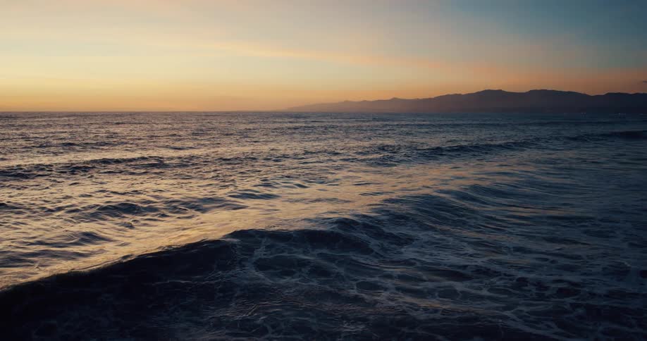 Waves gently roll in as the sunlight reflects on the water