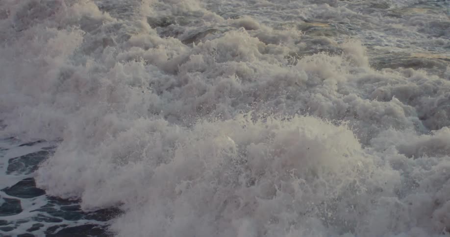 Huge wave rolling and splashing in as a person emerges from the foamy water