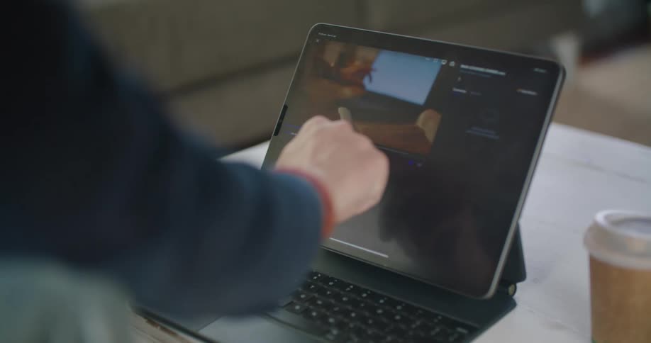 A man is sitting indoors and looking at a laptop