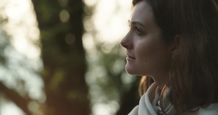 Young woman thinking and relaxing while sitting in the woods at sunset