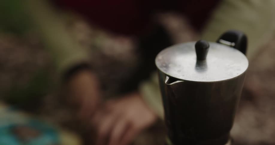 A person in a kitchen using a knife with a kettle with smoke in the foreground