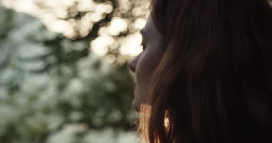 Young woman drinking hot beverage from a mug outdoors at sunset