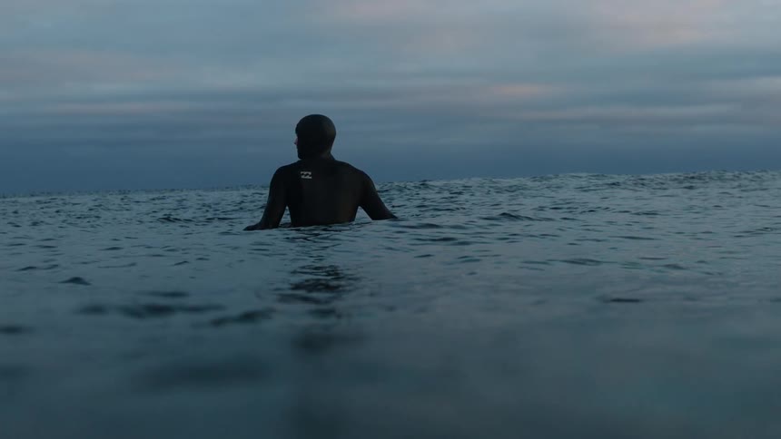 A man is floating in the water at sunset