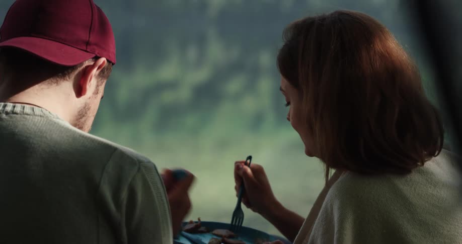A woman playfully feeds a man bites of food
