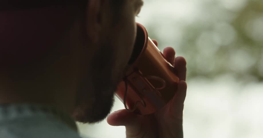 A man takes a drink from a copper mug while a woman smiles at him and chews