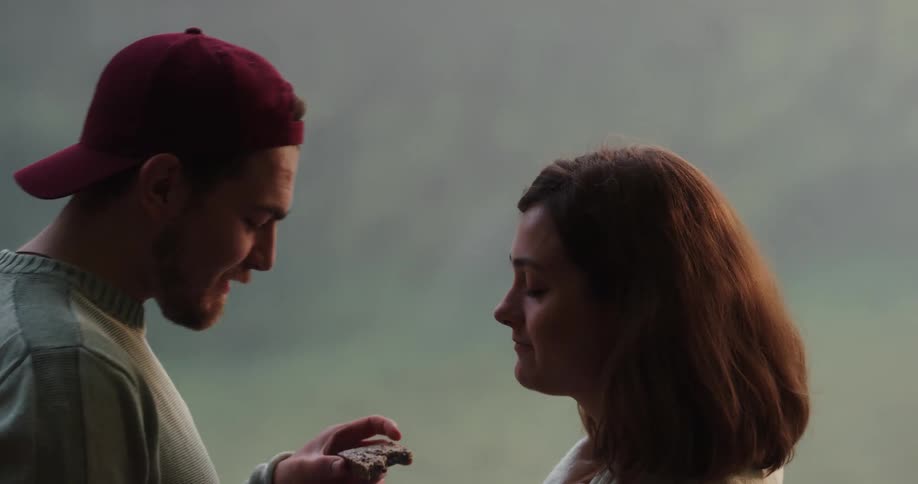 A man and woman are eating outdoors during the day