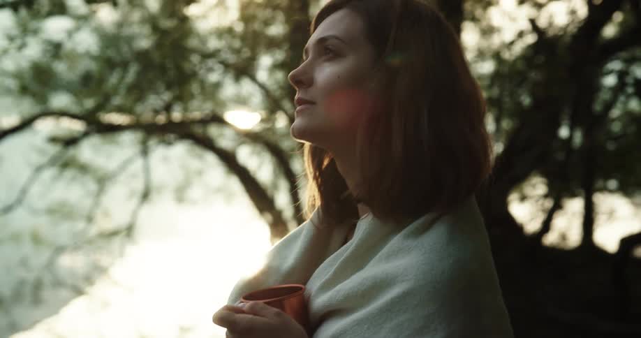 A woman and man are outdoors in a forest at dusk