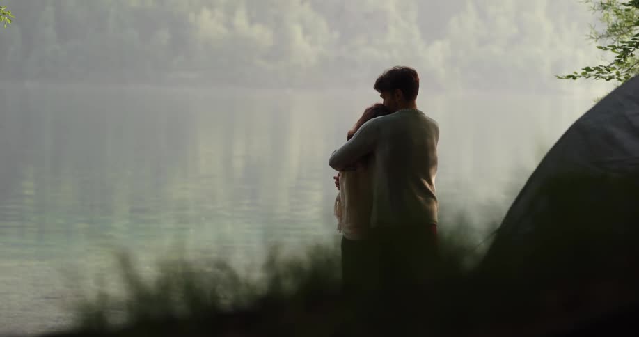 Husband walks up to his wife and hugs her outdoors