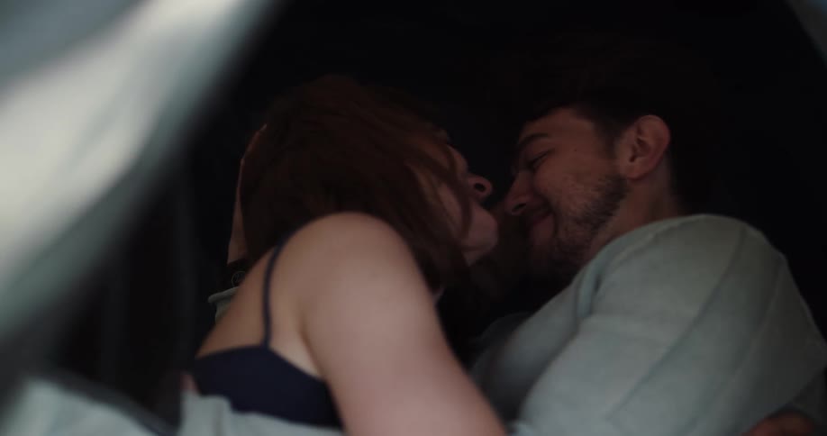 Young couple kissing and cuddling inside a tent in the forest