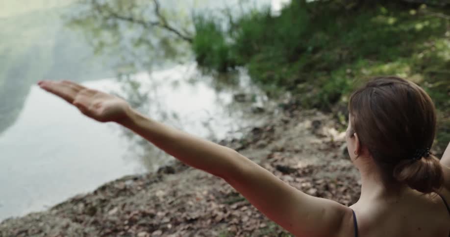 A woman is standing on a muddy lake short doing yoga