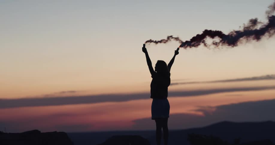 A woman standing with smoke flares