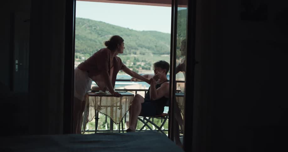 Woman takes the cigarette of a man smoking in the balcony and puts it out