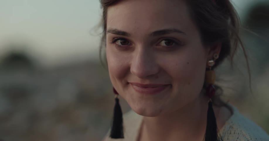 A woman is outdoors and is smiling