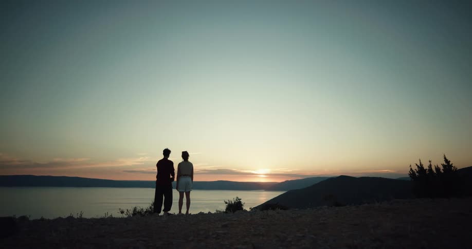 Husband and wife are hugging outdoors while the sun is setting