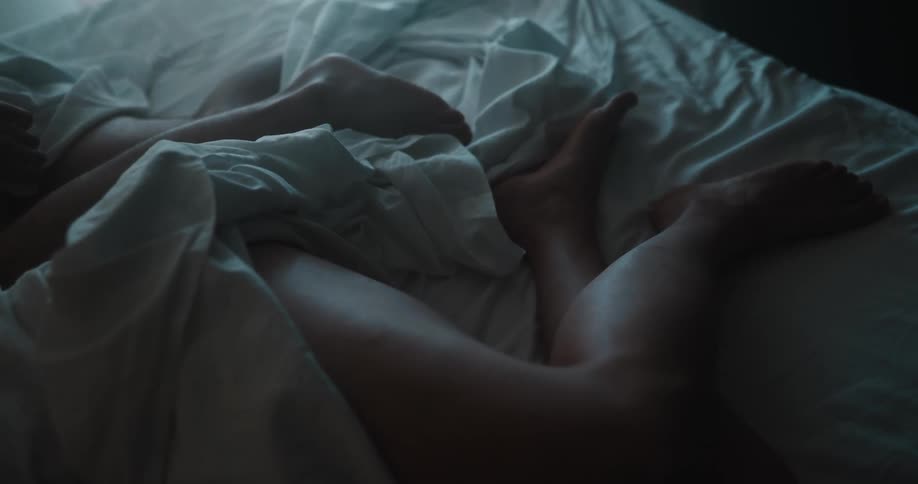 The legs of two people as they sleep in bed