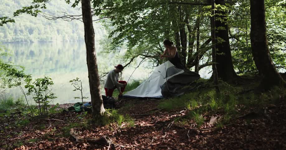 Man and woman are in the wilderness and setting up a tent