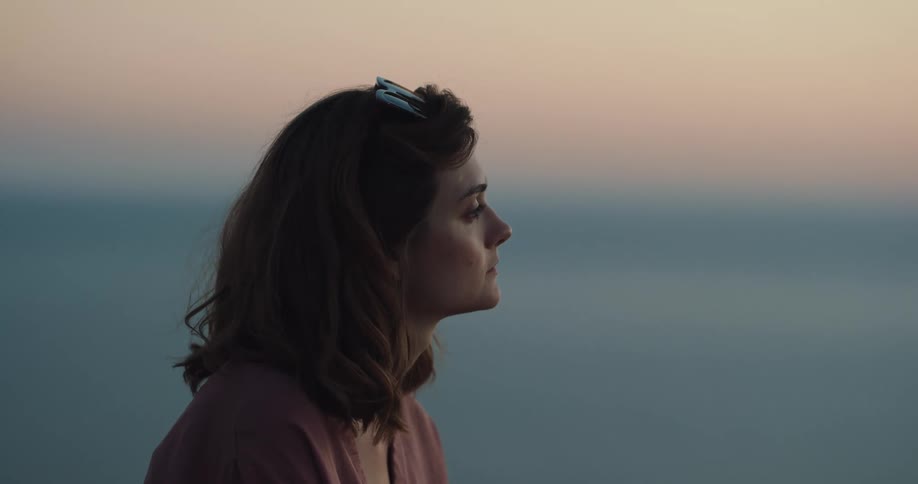 A woman looks off into the distance with sunglasses on her head