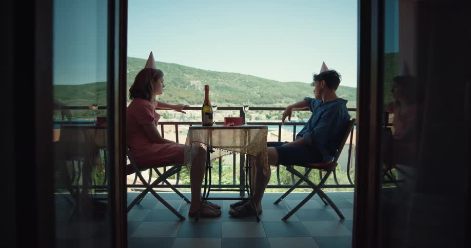 Young couple vacationing sitting on a table in the hotel room balcony