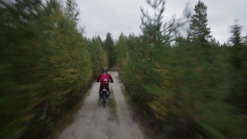A motorbike is moving fast down a dirt trail