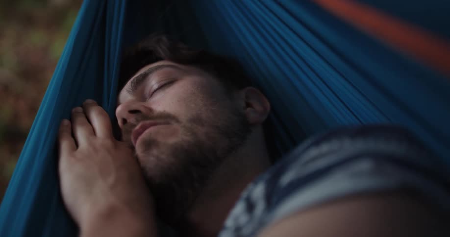 A man sleeps in a hammock outside