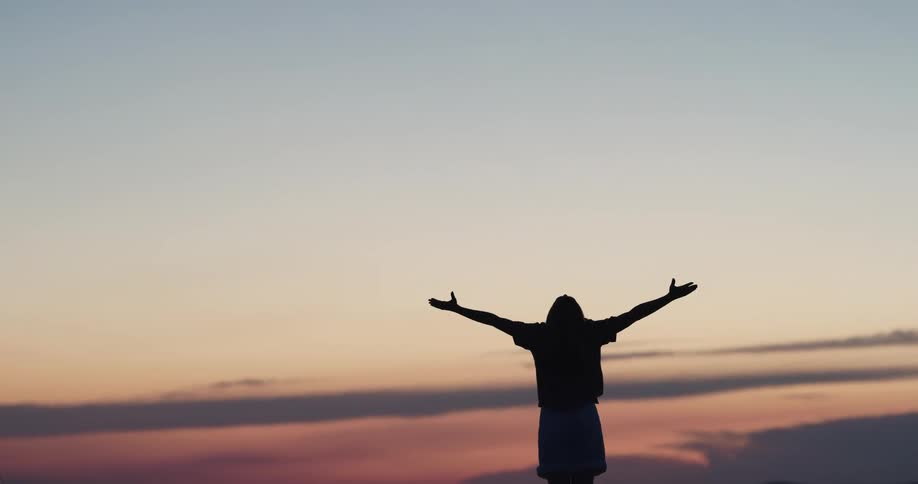 A woman is stretching outdoors at dusk